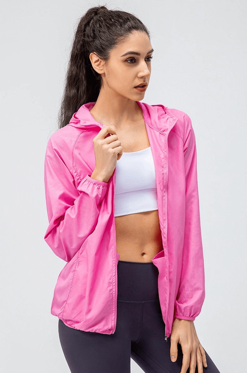 Woman wearing a pink waterproof windbreaker with hood, ideal for running outdoors. SF0136 breathable and windproof sports jacket.